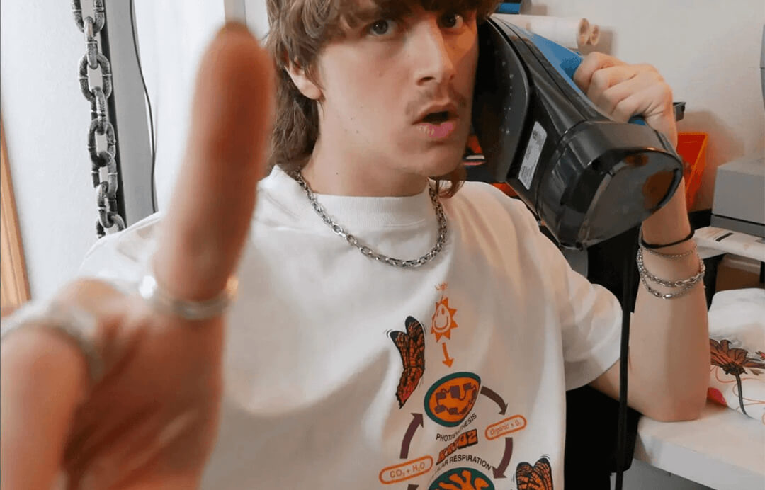 Kryoz on a phone wearing a shirt designed by Mitch Chadban